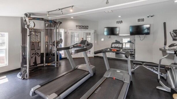 Un gimnasio con cintas de correr, una máquina de pesas y una pantalla de televisión.