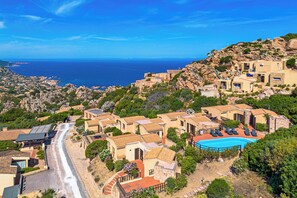 Ein Küstendorf mit Häusern mit Terrakotta-Dächern, einem Schwimmbad und Blick aufs Meer.