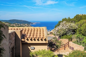 Ein Küstengebäude mit Terrakotta-Dachziegeln, einer Steintreppe und Blick auf das Meer.