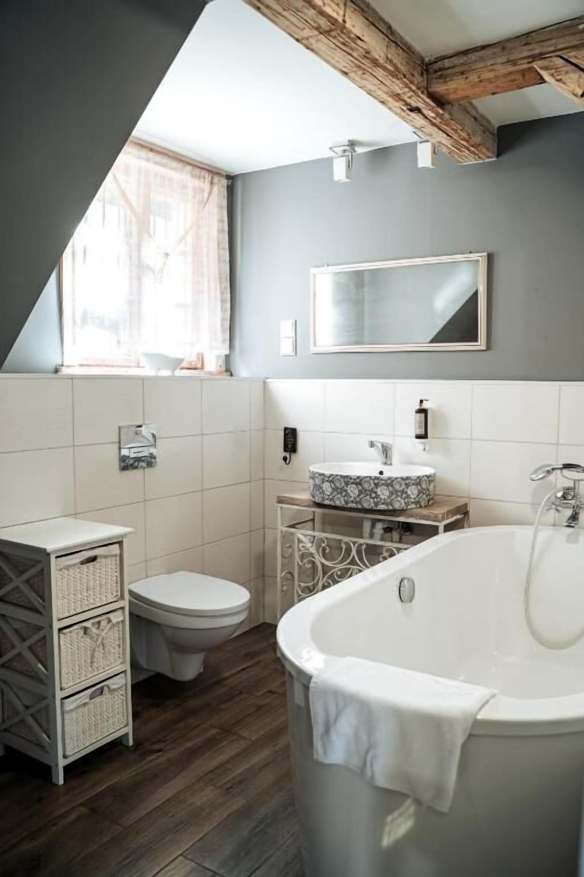 A modern bathroom with a freestanding bathtub, a toilet, and a vanity with a mirror.