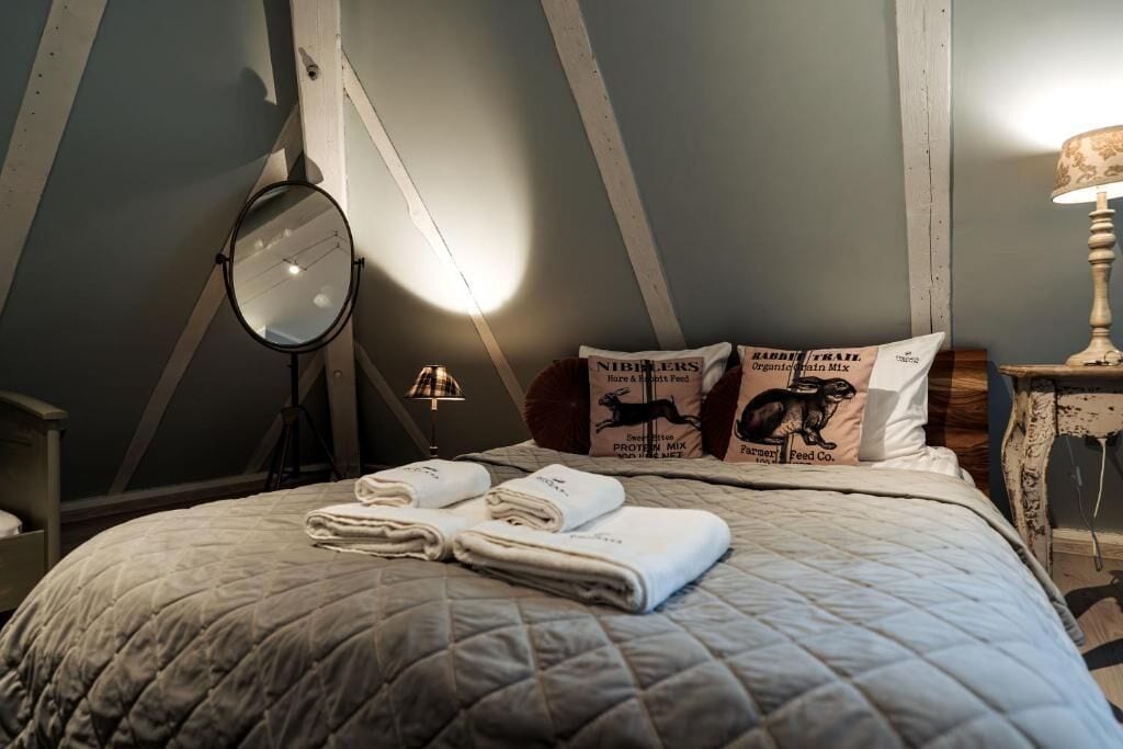 Un dormitorio con una cama, un espejo redondo, una lámpara y almohadas con estampados de animales.