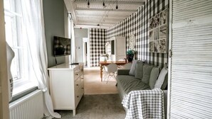 A room with a checkered wall, a sofa, a table, and a window with curtains.
