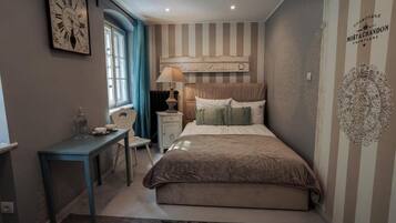 Un dormitorio con cama, escritorio, silla, ventana y un reloj de pared.