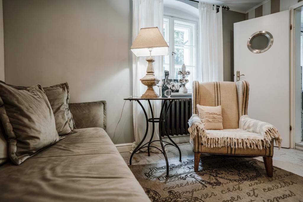 A cozy room with a sofa, a chair, a table with a lamp, and a radiator.