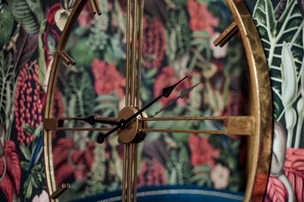 A wall clock with a floral background.
