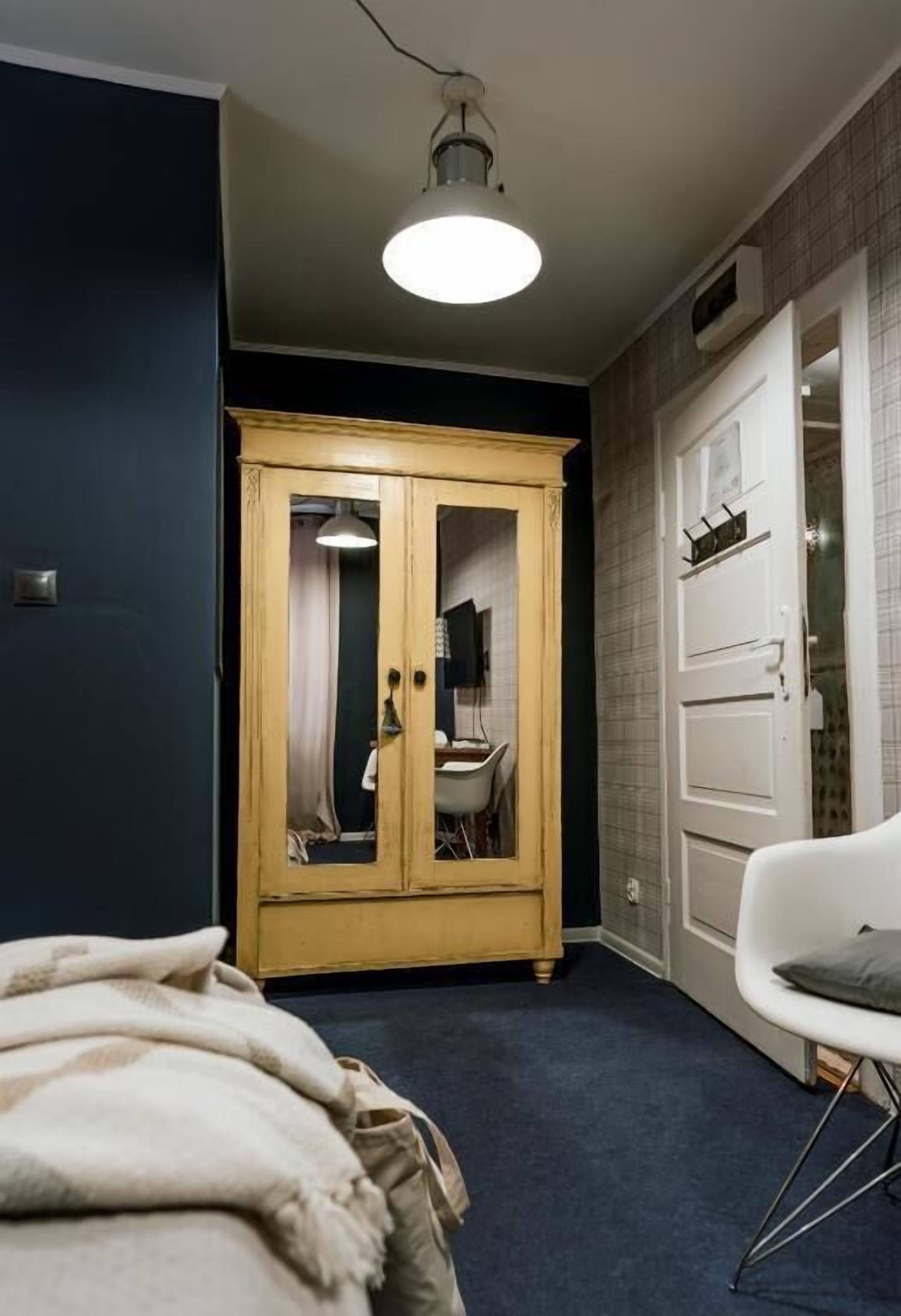 Een slaapkamer met een bed, een kledingkast, een stoel en een plafondlamp.