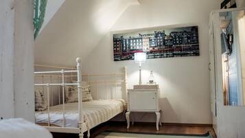 A bedroom with a bed, a nightstand, a lamp, a painting, and a door.