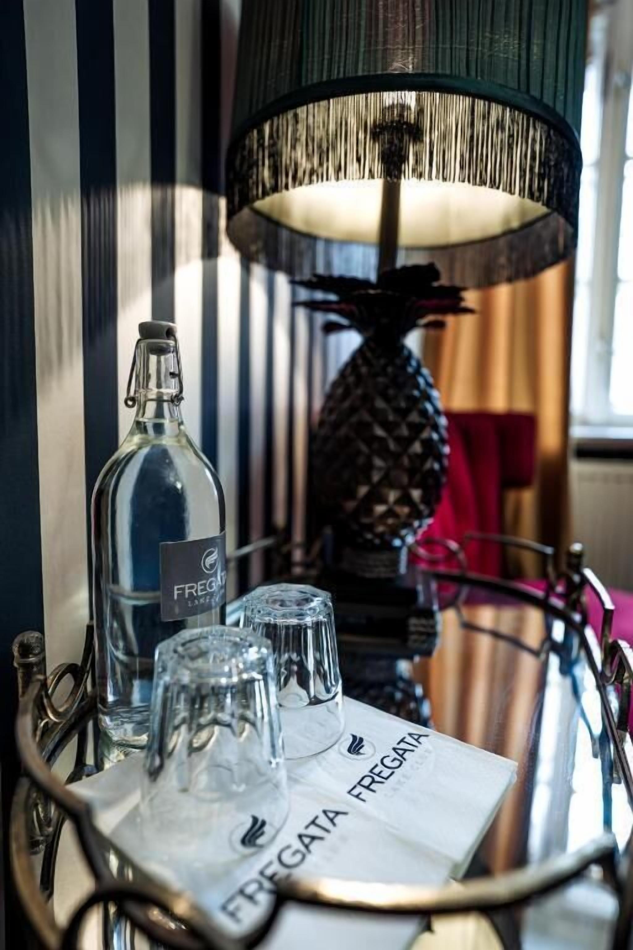 Une table avec une bouteille portant l’étiquette « FREGATA », deux verres et un menu intitulé « FREGATA FREGATA ».