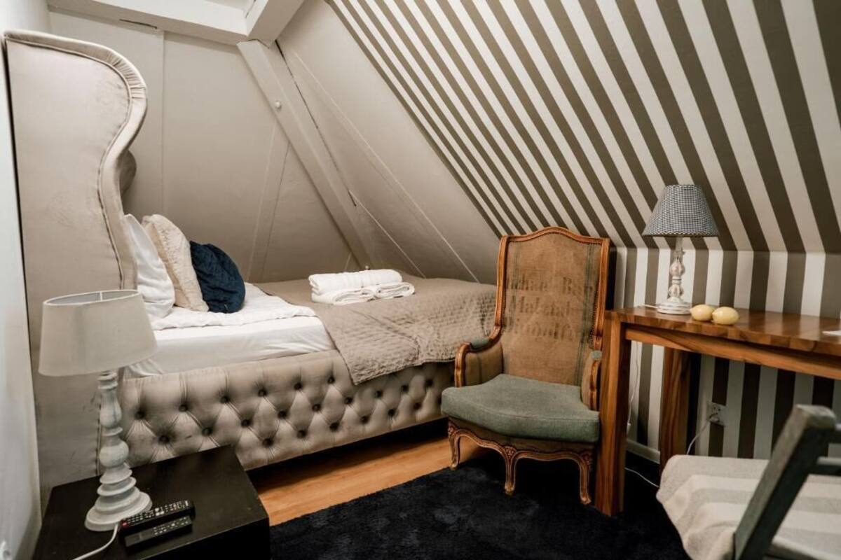 A bedroom with a bed, a chair, a desk, and a lamp.
