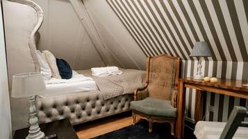 Un dormitorio con cama, una silla, un escritorio y una lámpara.