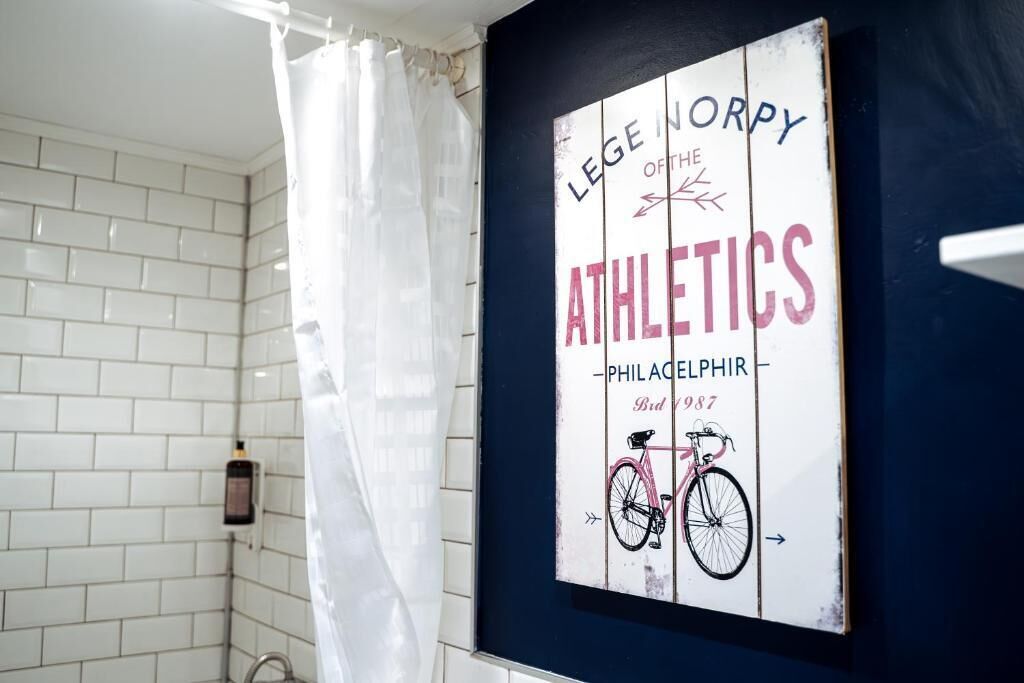 Ein Badezimmer mit weiß gefliesten Wänden, einer Duschvorhang und einem an der Wand befestigten Schild mit Text und einer Fahrradabbildung.