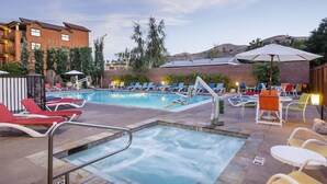 Ein Poolbereich mit Liegestühlen, einem Whirlpool und einem Gebäude im Hintergrund.