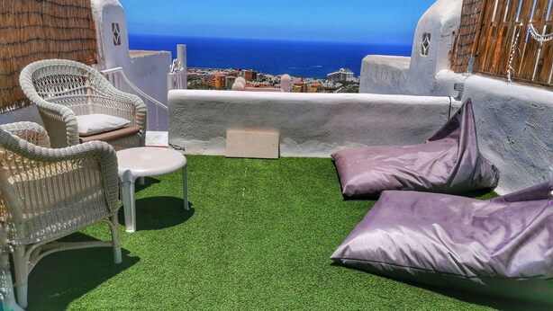Een terras met uitzicht op zee, rieten meubels en een tafeltje.