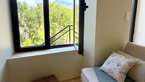 Quarto com uma janela grande, um sofá, uma cesta de vime e uma tomada.