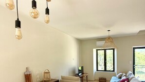 Uma sala de estar moderna com uma mesa de jantar de madeira, um sofá e uma televisão.