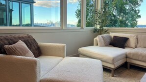 Ein modernes Wohnzimmer mit großem Fenster, einer Couch und einem Sessel.