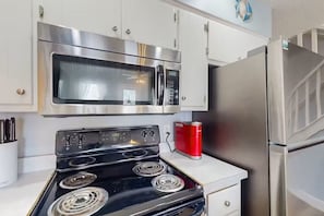 Eine Küche mit Edelstahlherd, Mikrowelle und Kühlschrank.
