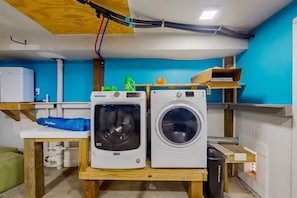 Ein Waschraum mit zwei Waschmaschinen, einer grünen Waschmittelflasche und einem weißen Kühlschrank.
