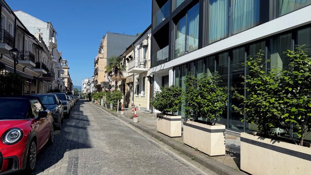Una calle adoquinada bordeada por vehículos estacionados y edificios.