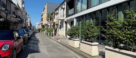 A cobblestone street lined with parked cars and buildings.
