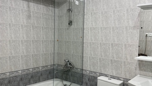 Un baño con ducha de vidrio, bañera blanca, inodoro y lavamanos.