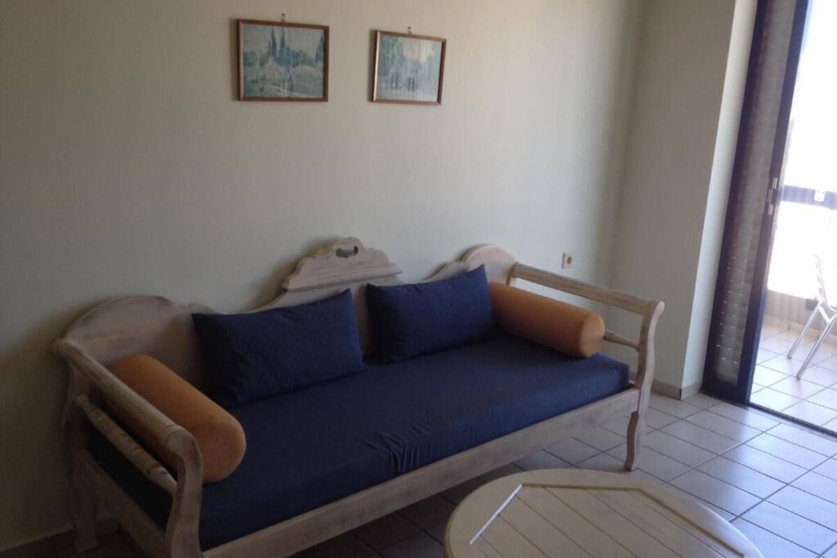 Um quarto com um sofá de madeira, uma mesinha e duas imagens emolduradas na parede.