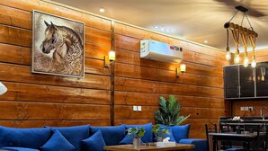 Ein Wohnzimmer mit Holzwand, einem blauen Sofa, einem Couchtisch und einem Deckenventilator.