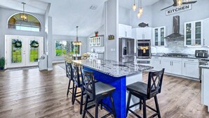 A modern kitchen with a large island, white cabinets, and a ceiling fan. - Resort-Style Estate w/ Heated Pool, Theater & Pickleball (Seminole)