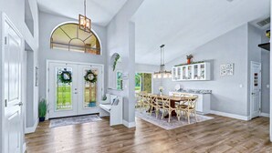 A spacious kitchen with a dining area, wooden flooring, and a high ceiling with exposed beams. - Resort-Style Estate w/ Heated Pool, Theater & Pickleball (Seminole)