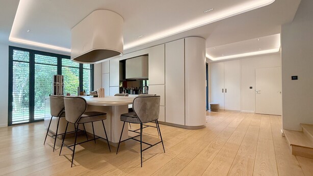 Una cucina moderna con isola centrale, sgabelli da bar e una grande finestra.