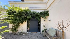 Un cortile lastricato con una porta, piante in vaso e una panchina.