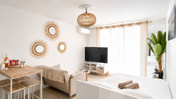 Une pièce moderne et bien éclairée, comprenant un canapé, un téléviseur, une table à manger et un lit.