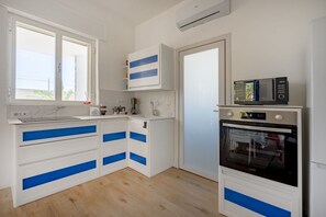 Eine Küche mit weißen Schränken, blauen Akzenten, einer Mikrowelle und einem Backofen.
