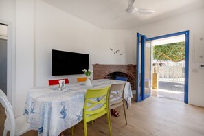 Ein Essbereich mit einem für zwei Personen gedeckten Tisch, einem an der Wand befestigten Flachbildfernseher und einem Kamin aus Ziegelsteinen.