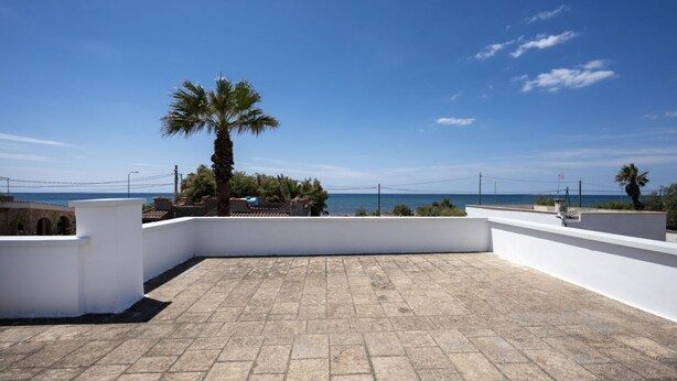 A rooftop terrace with a clear view of the sea, white walls, and a palm tree. - GuestHost - Villa Flamina (Marina di Lizzano)