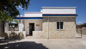 A villa with a stone facade, a tiled roof, and a paved entrance area. - GuestHost - Villa Flamina (Marina di Lizzano)