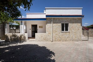 Eine Villa mit Naturstein-Fassade, einem Ziegeldach und einem gepflasterten Eingangsbereich.