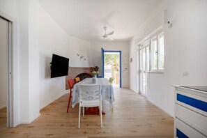 Ein Zimmer mit Kamin, Esstisch mit Stühlen, einem an der Wand befestigten Fernseher und einer zur Außenseite führenden Tür.