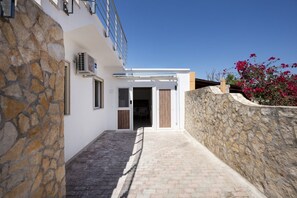 A stone-walled building with a paved entrance, a small covered area, and a clear sky. - GuestHost - Villa Flamina (Marina di Lizzano)