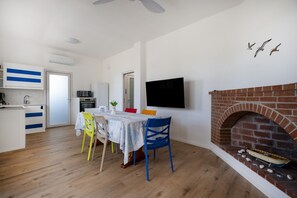 Ein modernes Wohnzimmer mit Kamin, einem an der Wand befestigten Flachbildfernseher und einem Essbereich mit Tisch und Stühlen.
