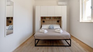 A bedroom with a bed, a wardrobe, a mirror, and a window. - GuestHost - Villa Flamina (Marina di Lizzano)