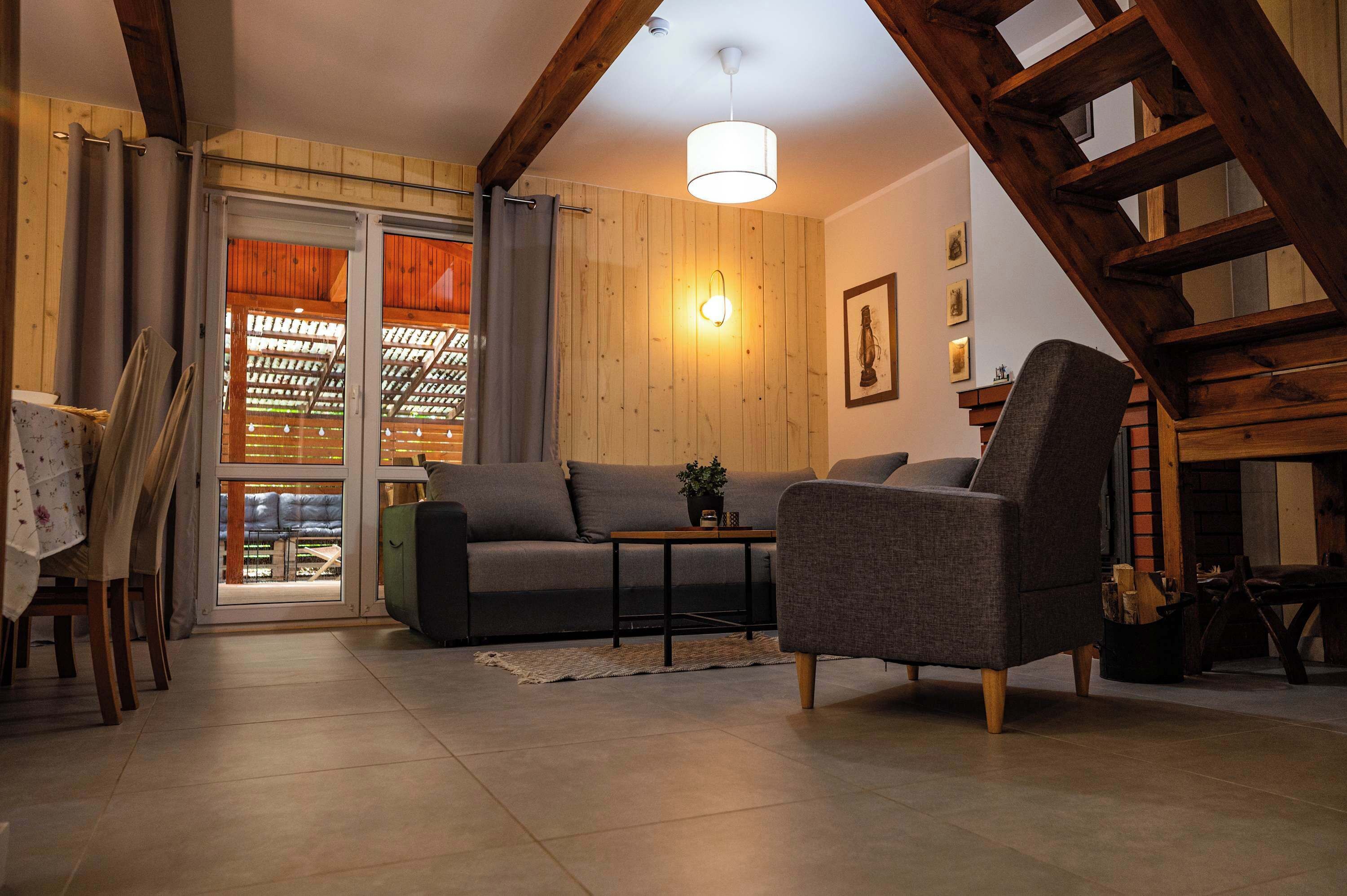 Een gezellige woonkamer met een bank, fauteuil en een tafel met een lamp.