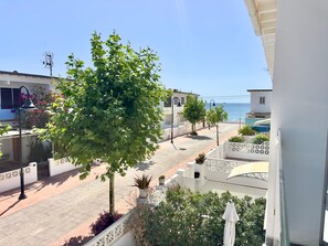 Un balcone con vista sul mare, un albero e un edificio bianco con un balcone.