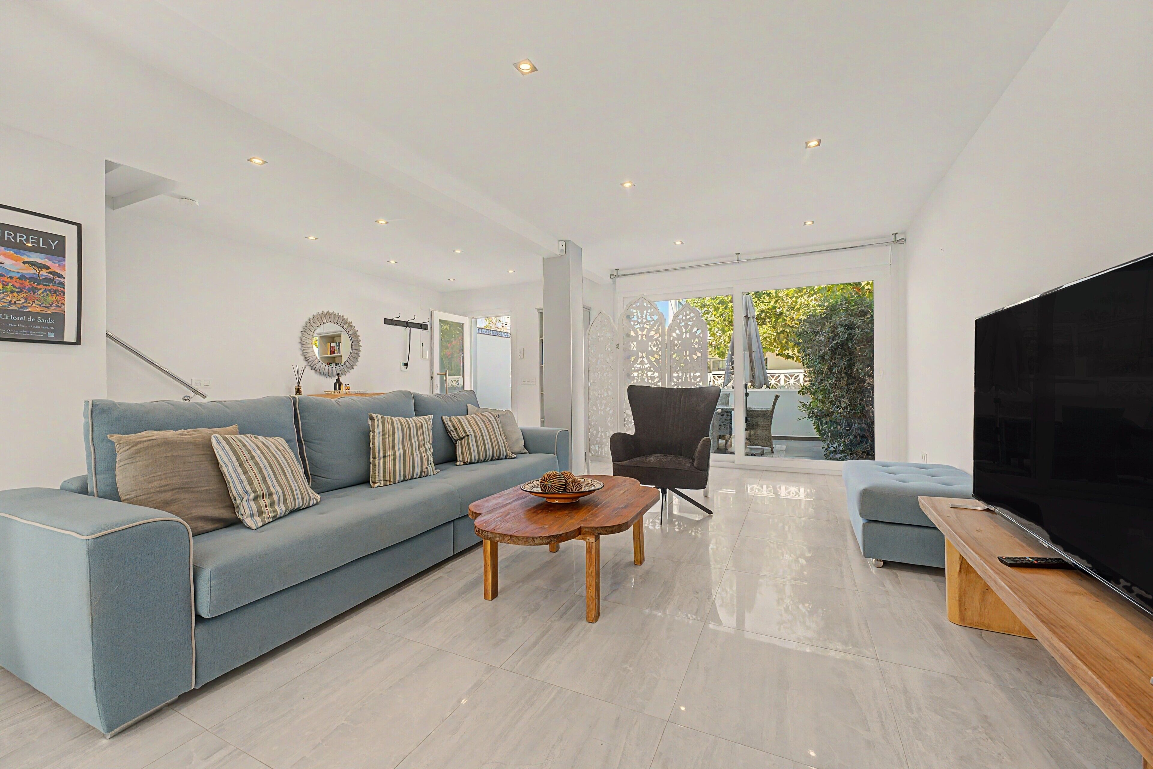 Una sala moderna con sofá, sillón, mesa de centro y televisor.
