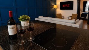 A modern kitchen with a built-in stove, a wine bottle, and glasses on the counter. - Urban Lux Apartment | Heart of Town (Warrington)