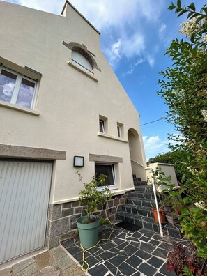A building with a stone staircase leading to a door, a small window, and a potted plant in the foreground. - Vacation home—a central base for exploring northern Finistère, with the sea just 4 km away (Henvic)