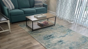 A living room with a teal sofa, a coffee table, a rug, and a lamp. - Spacious 3-bedroom townhome, 3 minute walk to the beach, pet-friendly (Myrtle Beach)