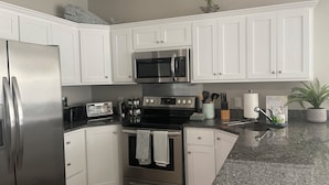 A kitchen with white cabinets, stainless steel appliances, granite countertops, and a potted plant. - Spacious 3-bedroom townhome, 3 minute walk to the beach, pet-friendly (Myrtle Beach)