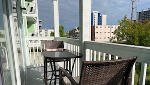 A balcony with a table and chairs, a white railing, and a view of buildings. - Spacious 3-bedroom townhome, 3 minute walk to the beach, pet-friendly (Myrtle Beach)