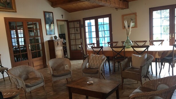 A cozy room with wicker furniture, wooden tables, and a large window.
